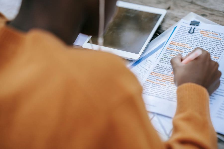 Handwritten study notes with key sentences highlighted beside an open textbook.