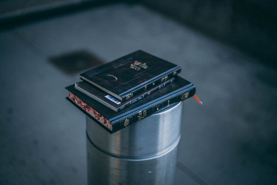 A short stack of hardback books on a plain surface.