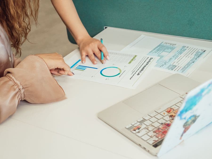 Two people comparing printed documents page by page.